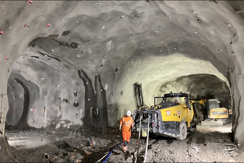 Inside the Coire Glas tunnel - there is a worker in PPE and two diggers in a very large grey tunnel